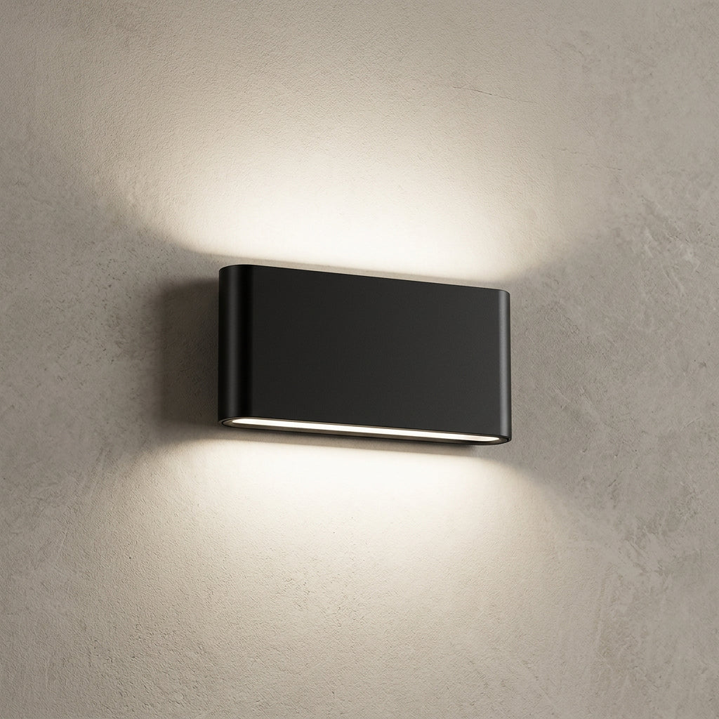 A modern rectangular black wall-mounted light fixture with a horizontal LED strip, shown illuminated against a white wall.